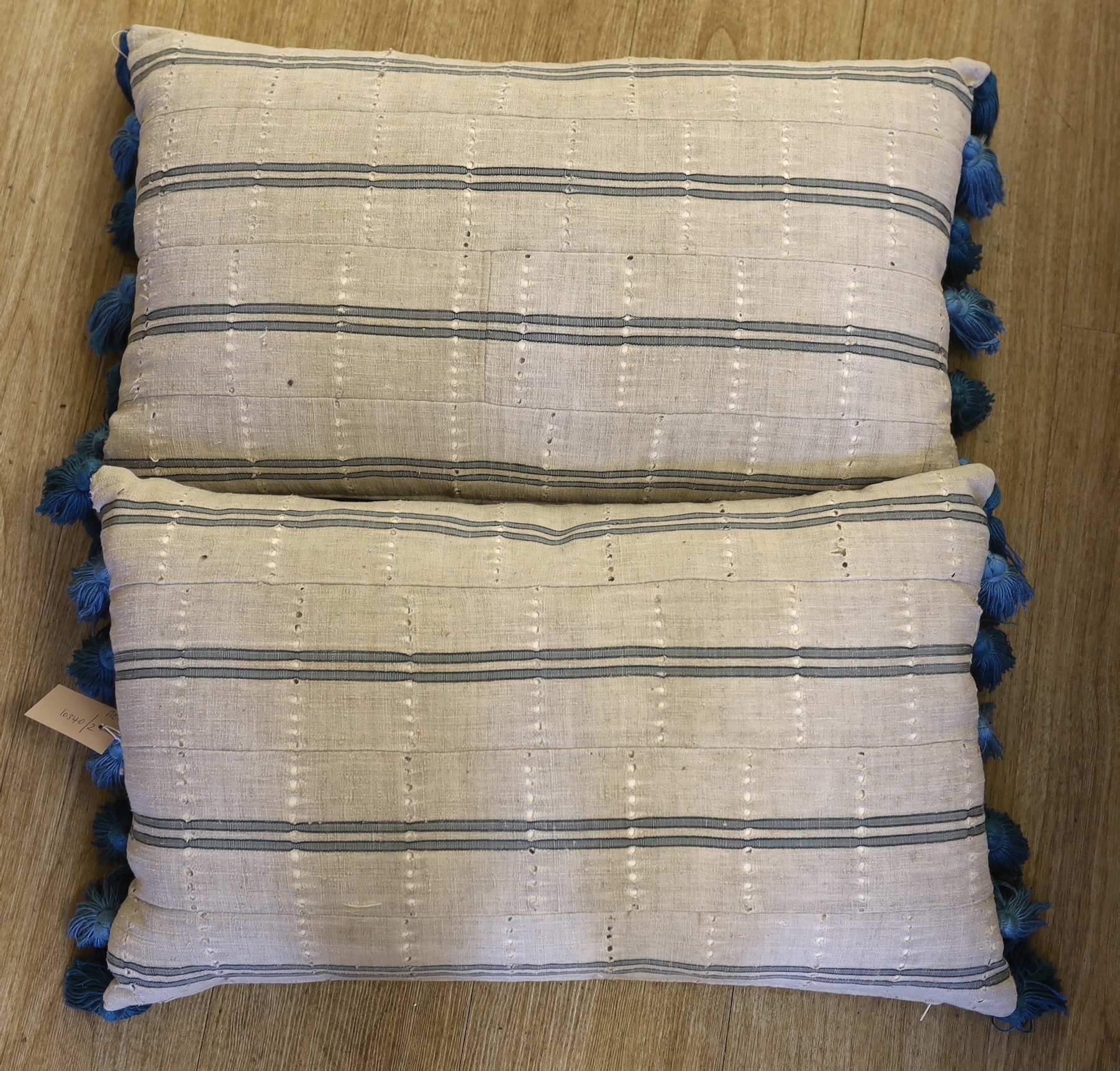 A pair of vintage Yoruba cushions with bamboo tassels, each 65cm wide